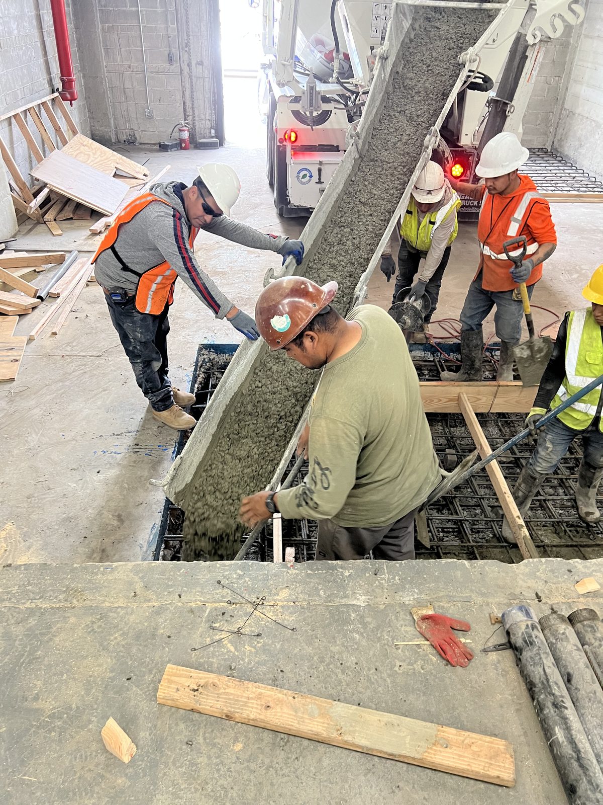 JBS concrete crew pouring structural slab from ready-mix truck with rebar matting