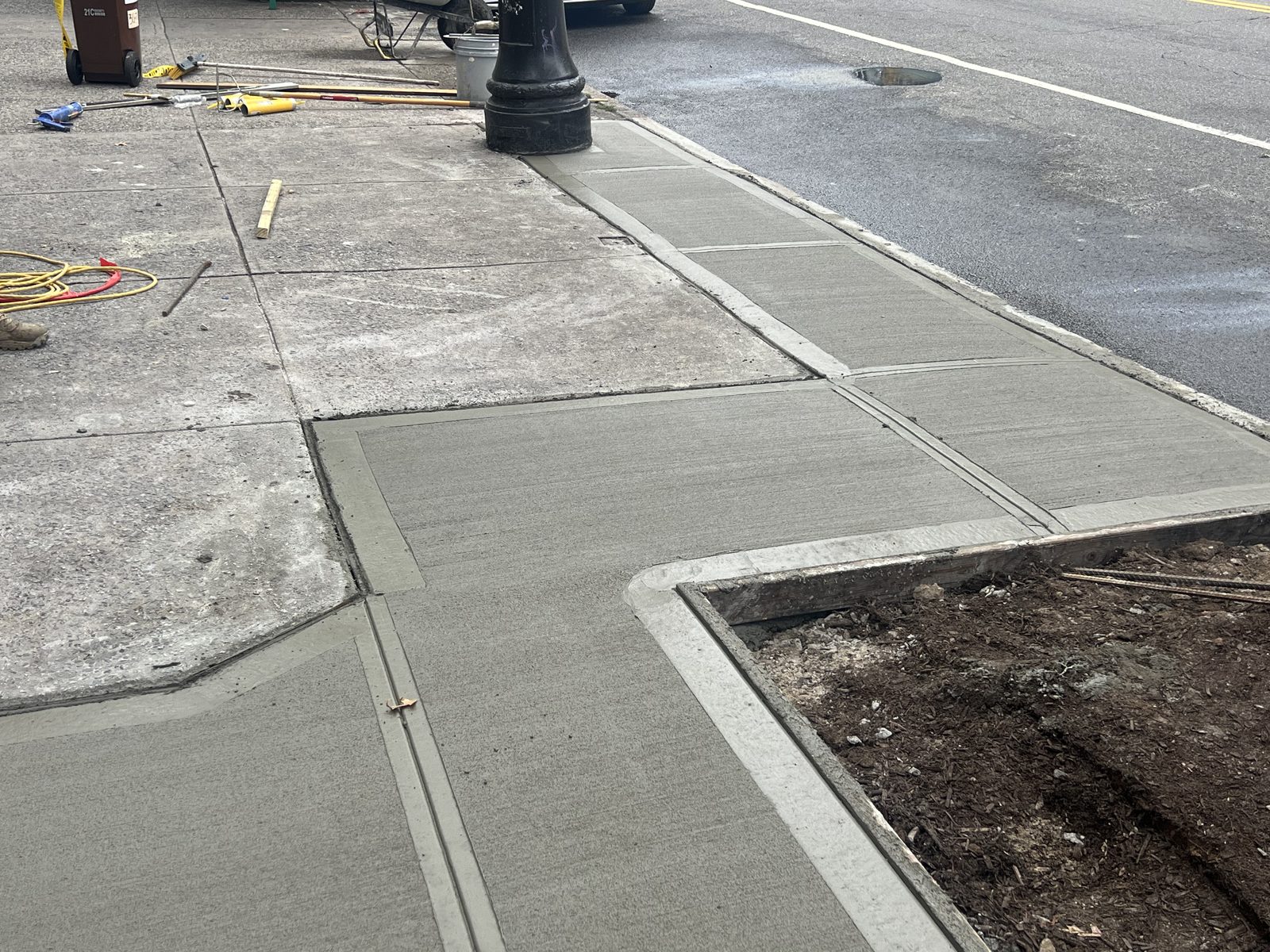 JBS NYC sidewalk replacement with fresh broom-finished concrete around lamp post