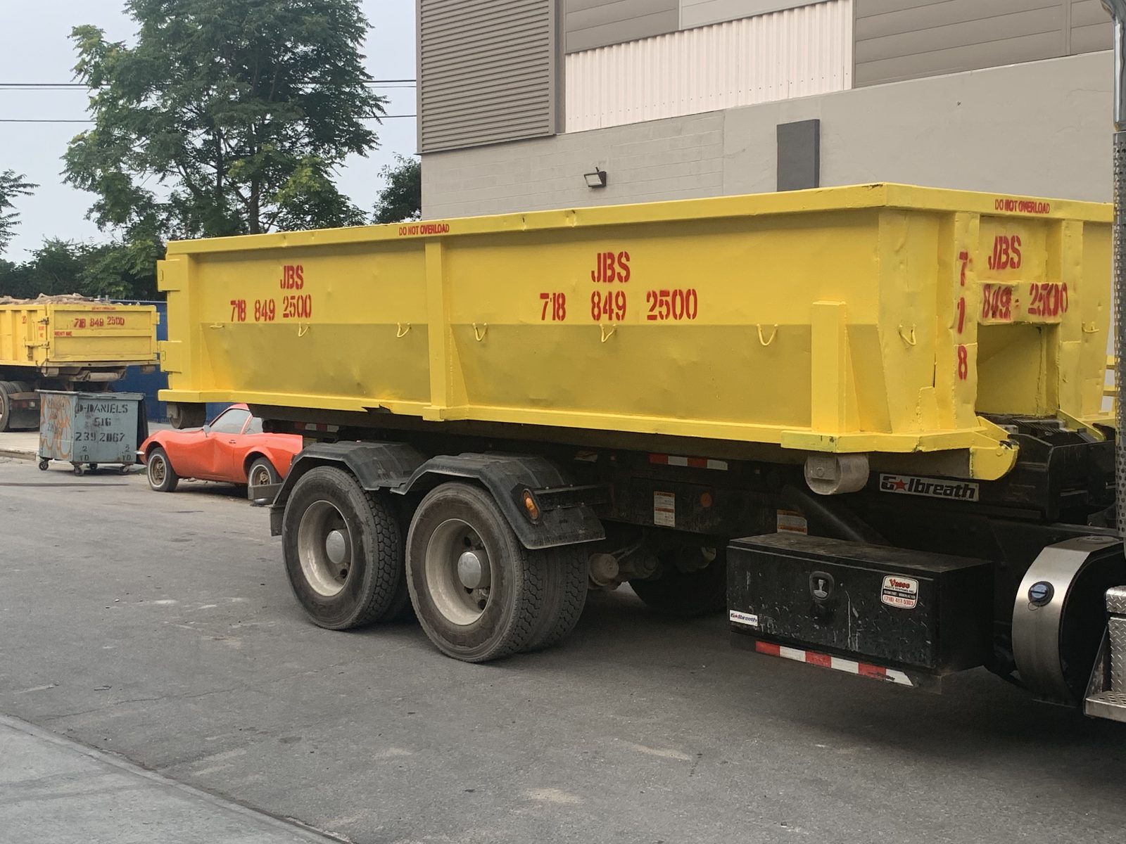 JBS 20 yard yellow roll-off dumpster loaded on truck for NYC delivery