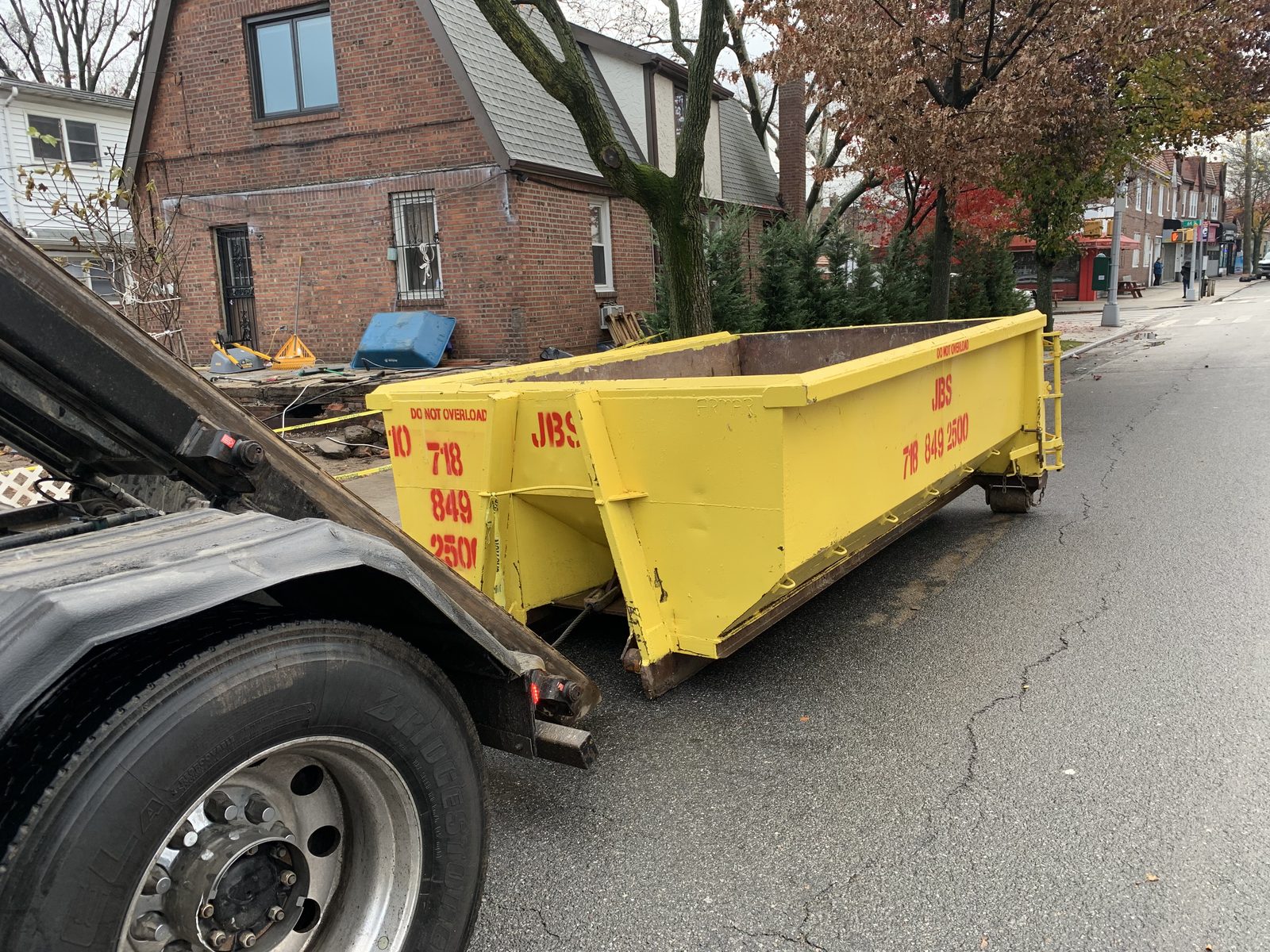 JBS yellow dumpster delivery to Queens residential brick home